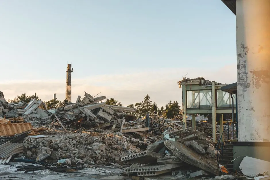 A dramatic scene of urban demolition with rubble and a standing tower under a clear sky.
